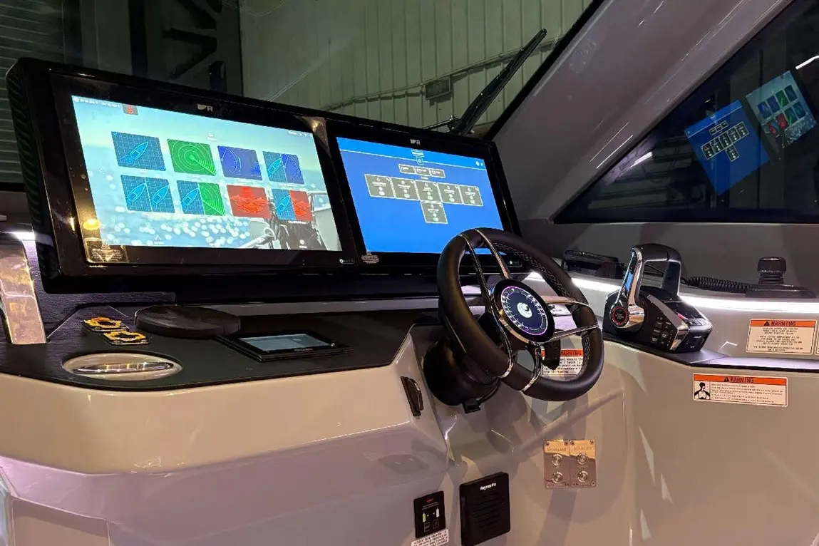 High-tech boat dashboard with dual screens displaying navigation data and controls, featuring steering wheel and communication device.